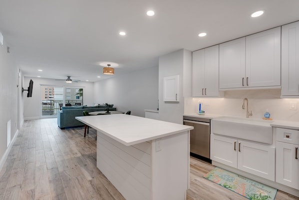 A modern kitchen with white cabinetry, a central island, and a dining area with a sofa.