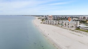 Un hotel frente al mar con varias edificaciones, una playa y una vista despejada del océano.