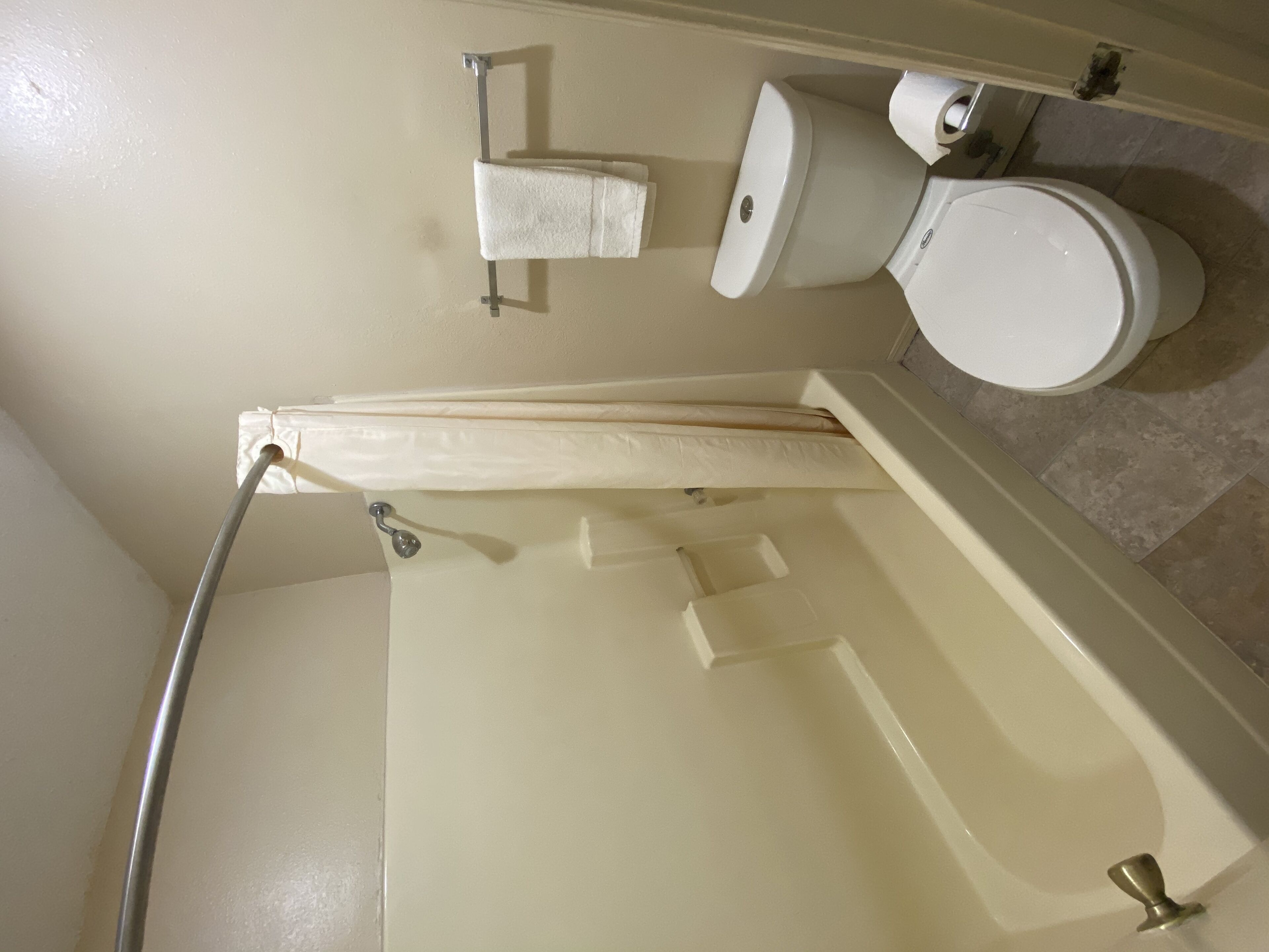 Un baño con bañera, inodoro y toallero.