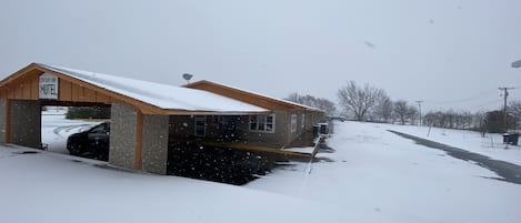 Un motel doté d’un parking couvert et d’une allée recouverte de neige.