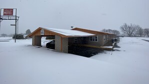 Motel A Century Inn mit überdachtem Parkplatz und verschneiter Landschaft.