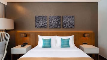 Habitación de hotel con una cama grande, dos mesitas de noche, una lámpara y tres obras de arte colgadas en la pared.
