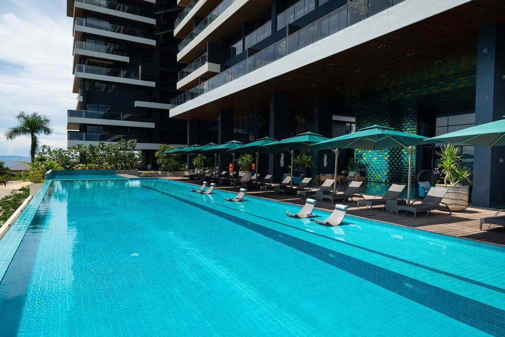 Un hotel moderno con una piscina larga, tumbonas y sombrillas.