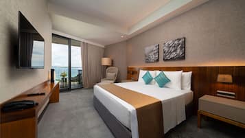 Ein Hotelzimmer mit einem großen Bett, einem Schreibtisch, einem Stuhl, einem Fernseher und einem Balkon mit Aussicht.