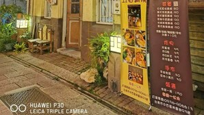 Un edificio tradicional con un balcón, faroles y un cartel anunciando comidas.