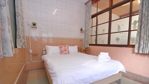 Un dormitorio con cama, mesita de noche, ventana con cortinas y estante con plantas en la pared.