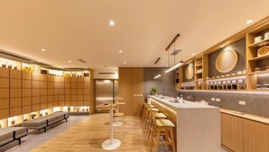 Un área de bar moderna con paneles de madera, taburetes y una barra con varios objetos.