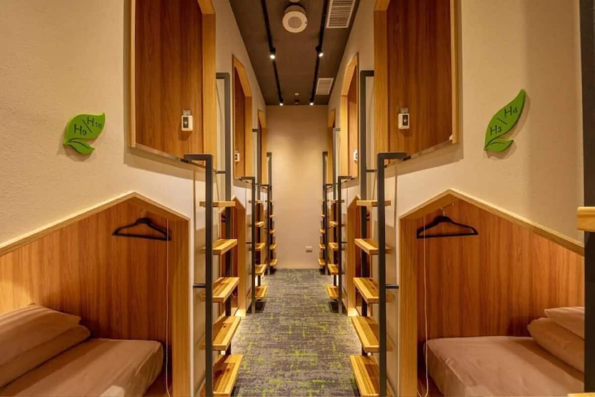 Un couloir d’hôtel aux murs en bois, au sol recouvert de moquette, et une allée centrale bordée de bancs en bois.