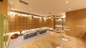 Un moderno vestíbulo de hotel con taquillas de madera, zonas de estar y una recepción.