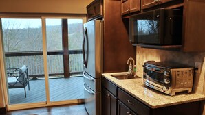 A kitchen with a stainless steel refrigerator, a microwave, and a toaster oven. There is a sliding glass door leading to a deck with outdoor furniture. - 7 BR, 7.5 Bath Home with Hot Tub close to all of the Branson Fun! (Branson)