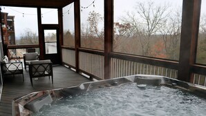 A hot tub on a wooden deck with chairs and a view of trees. - 7 BR, 7.5 Bath Home with Hot Tub close to all of the Branson Fun! (Branson)