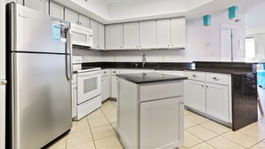 Een moderne keuken met witte kasten, roestvrijstalen apparatuur en een zwart aanrecht eiland.