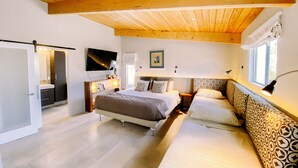 A bedroom with a large bed, a sofa, a TV, and a window with curtains. - Mid Century Modern Home || 28 day minimum  (Palm Springs)