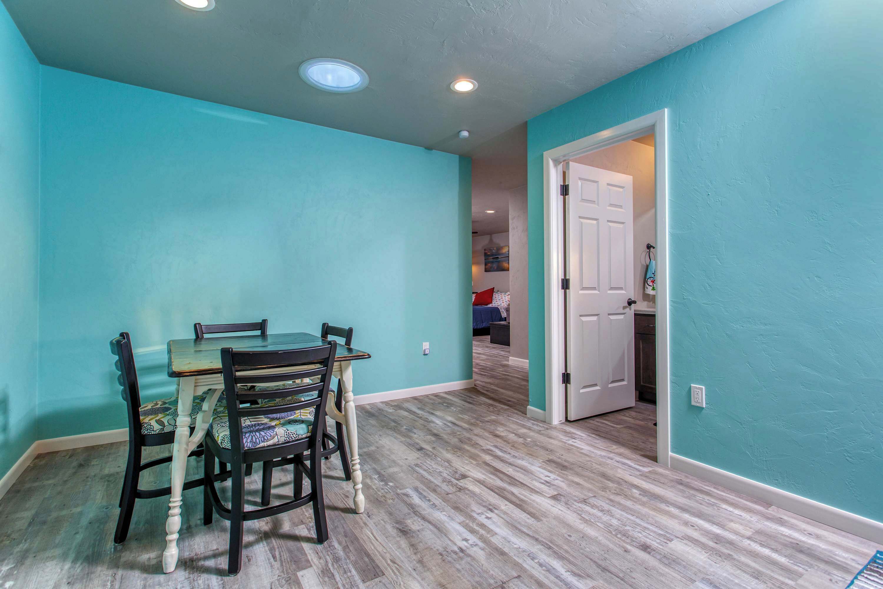 A dining area with a table and chairs, a door leading to another room, and a light switch on the wall.