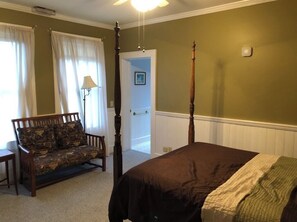 A bedroom with a four-poster bed, a wooden bench, and a lamp.