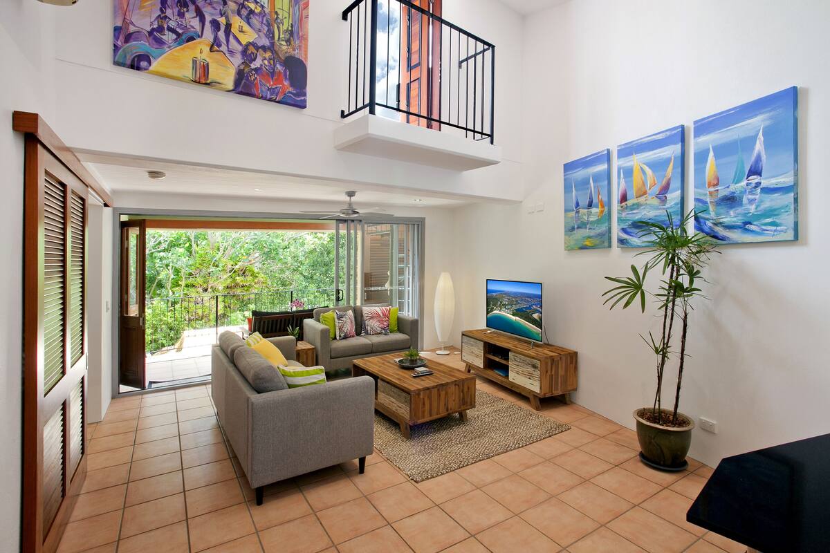 Een moderne woonkamer met een bank, salontafel, televisie en kunstwerk.