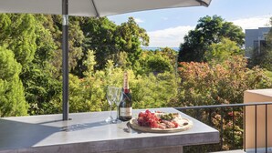 Un balcon avec une table dressée pour un repas, une bouteille de vin et deux verres.