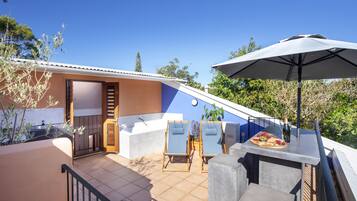 Terraza en la azotea con jacuzzi, sillones de descanso y una mesa con una botella y frutas.
