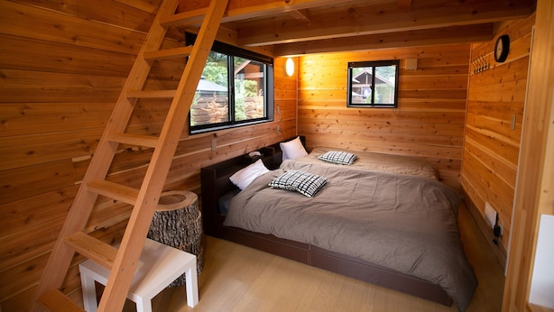 A wooden cabin bedroom with a bed, a ladder, and a small table. - Shioya Spa (Minakami)