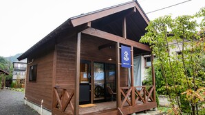 A wooden building with a porch, a sign indicating it's a spa, and a view of a garden. - Shioya Spa (Minakami)
