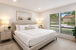 A bedroom with a bed, bedside tables, lamps, a framed picture, and a window with blinds. - PGA National Home on Golf Course by Guaranteed Rental™ (Palm Beach Gardens)