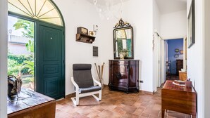 A spacious hallway with a green door, a white chair, a wooden cabinet, and a mirror. - Blumarine house on the sea, parking and wi.fi (Avola)