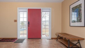 A room with a red door, a bench, and a framed picture on the wall. - Wind River Place- Mountain views, Cozy nights, Sleeps 6! (Lander)
