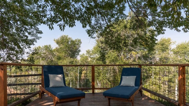 A wooden deck with two blue lounge chairs and a wooden railing. - Wind River Place- Mountain views, Cozy nights, Sleeps 6! (Lander)