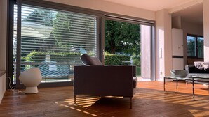 A modern living room with a sofa, a coffee table, and a large window with blinds.