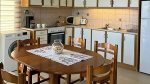 Keittiössä on puukehikoiset kaapit, ruokapöytä tuoleineen, pesukone ja mikroaaltouuni.