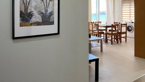 Käytävällä on seinällä kehystetty taideteos, ja se johtaa ruokailutilaan, jossa on tuoleja ja pöytä.