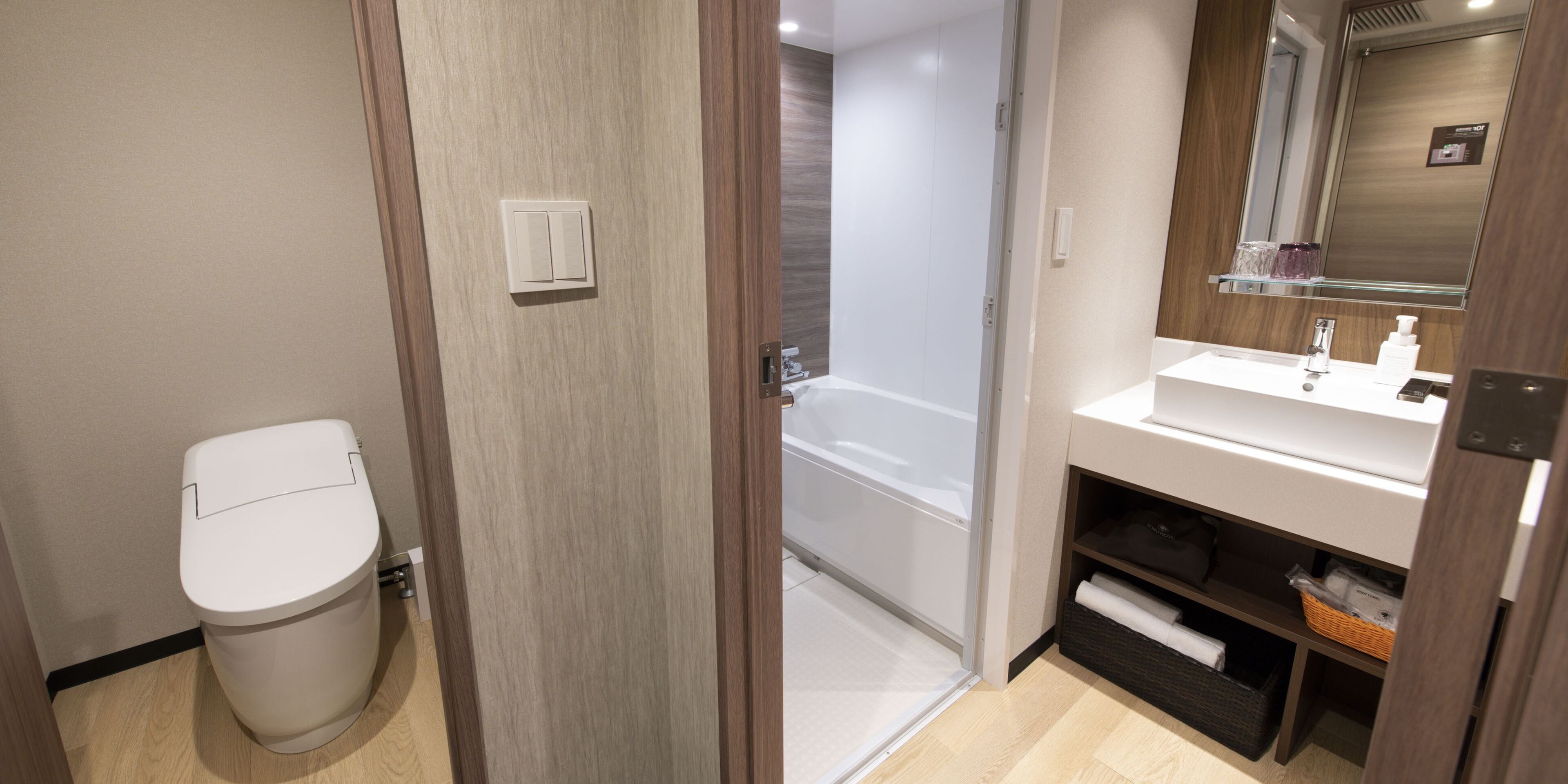 A modern bathroom with a toilet, a shower, and a sink with a mirror.