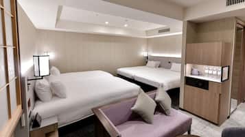 A hotel room with two beds, a sofa, a desk with a computer, and a minibar.