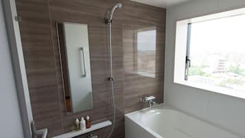 A modern bathroom with a bathtub, a shower, a large mirror, and a window with a city view.
