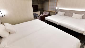 A hotel room with two beds, a desk, a chair, and a TV.
