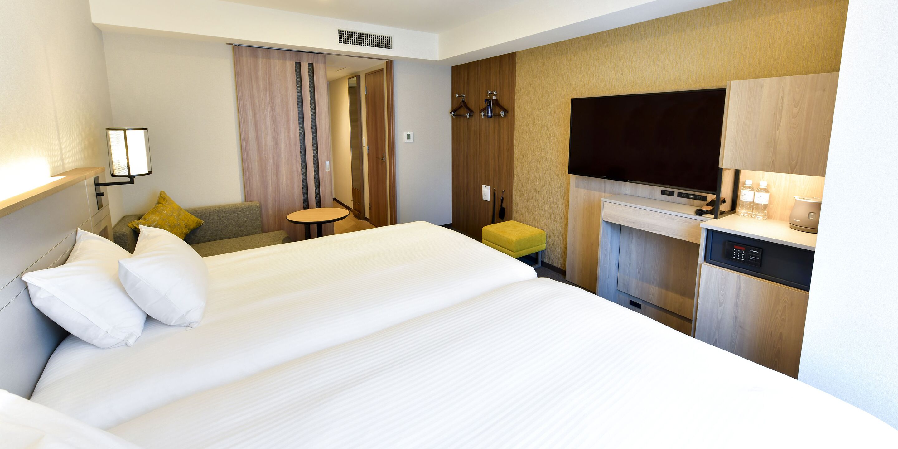 Habitación de hotel con una cama grande, una mesita, un sofá, un televisor y un rincón americano.
