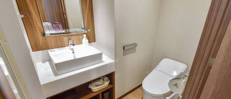 A modern bathroom with a white sink, mirror, and toilet.