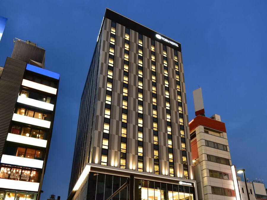 A modern hotel building with a prominent sign, multiple floors, and illuminated windows.