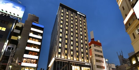 A modern hotel building with a prominent sign, multiple floors, and illuminated windows.
