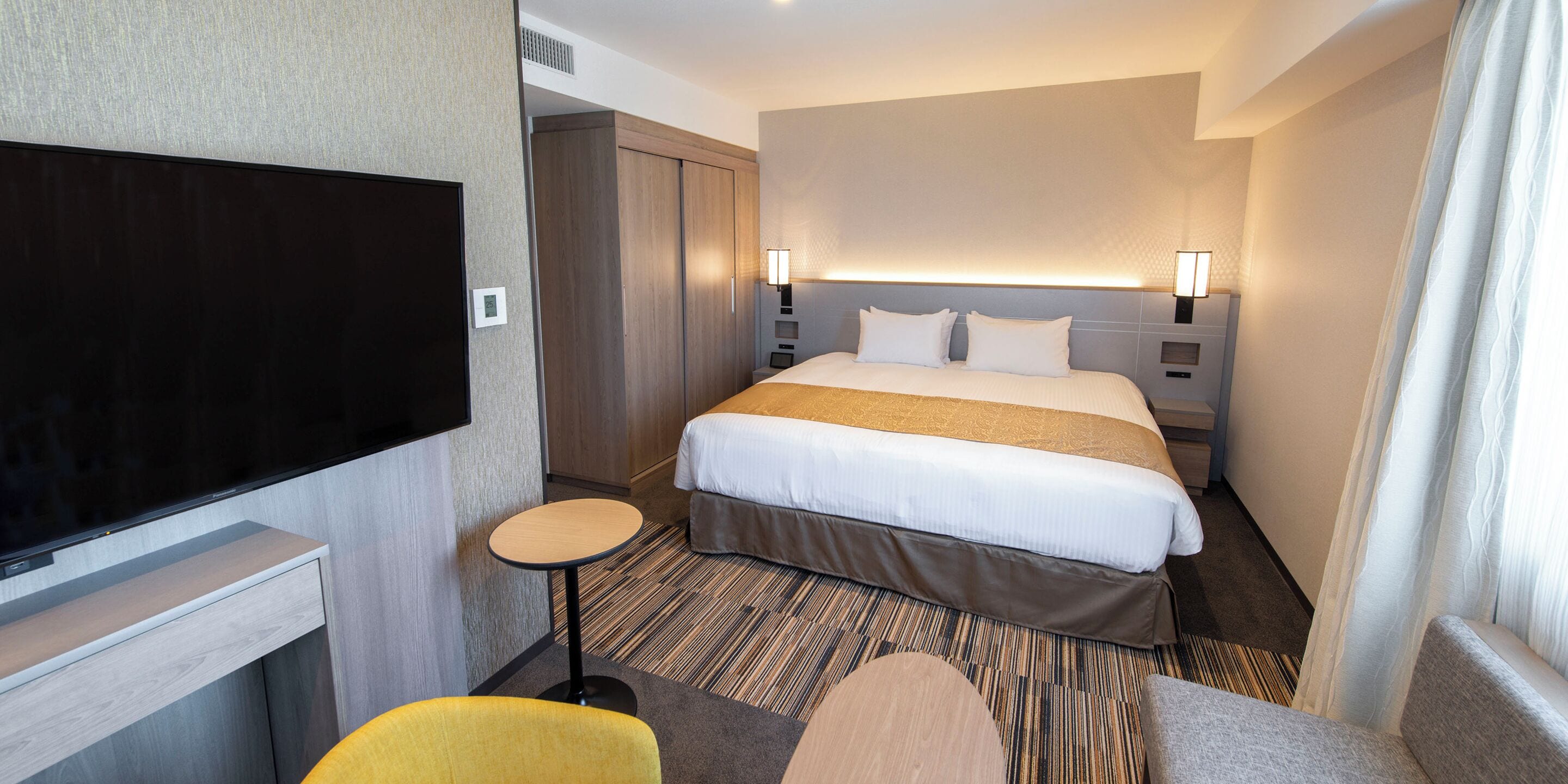Habitación de hotel con cama, televisión, una mesita y una silla.