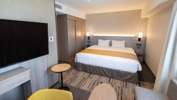 Habitación de hotel con cama, televisión, una mesita y una silla.