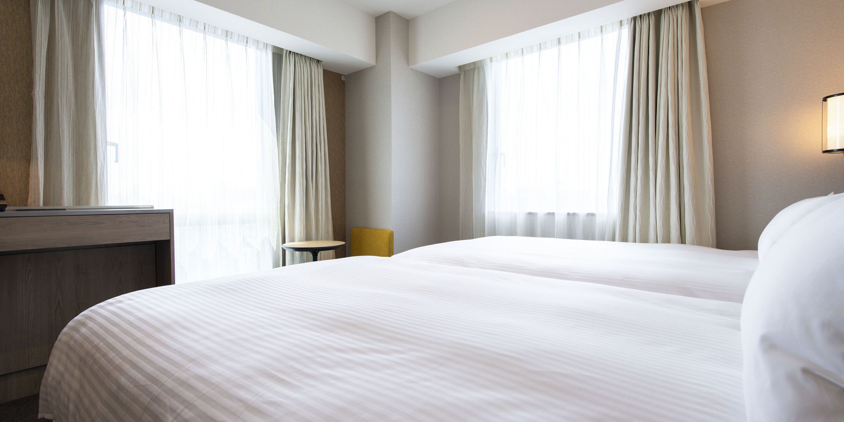Ein Hotelzimmer mit zwei Betten, einem kleinen Tisch und einem Stuhl.