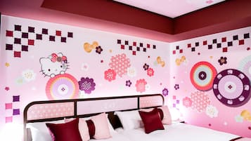 A bedroom with a bed, pillows, and a wall decorated with Hello Kitty and floral patterns.