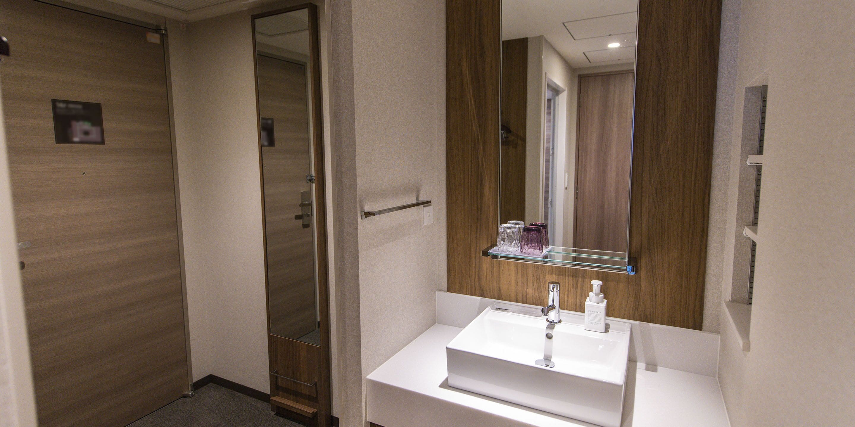 A bathroom with a white sink, a mirror, and a wooden door.