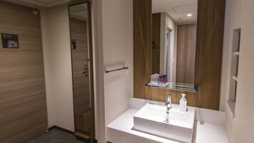 A bathroom with a white sink, a mirror, and a wooden door.