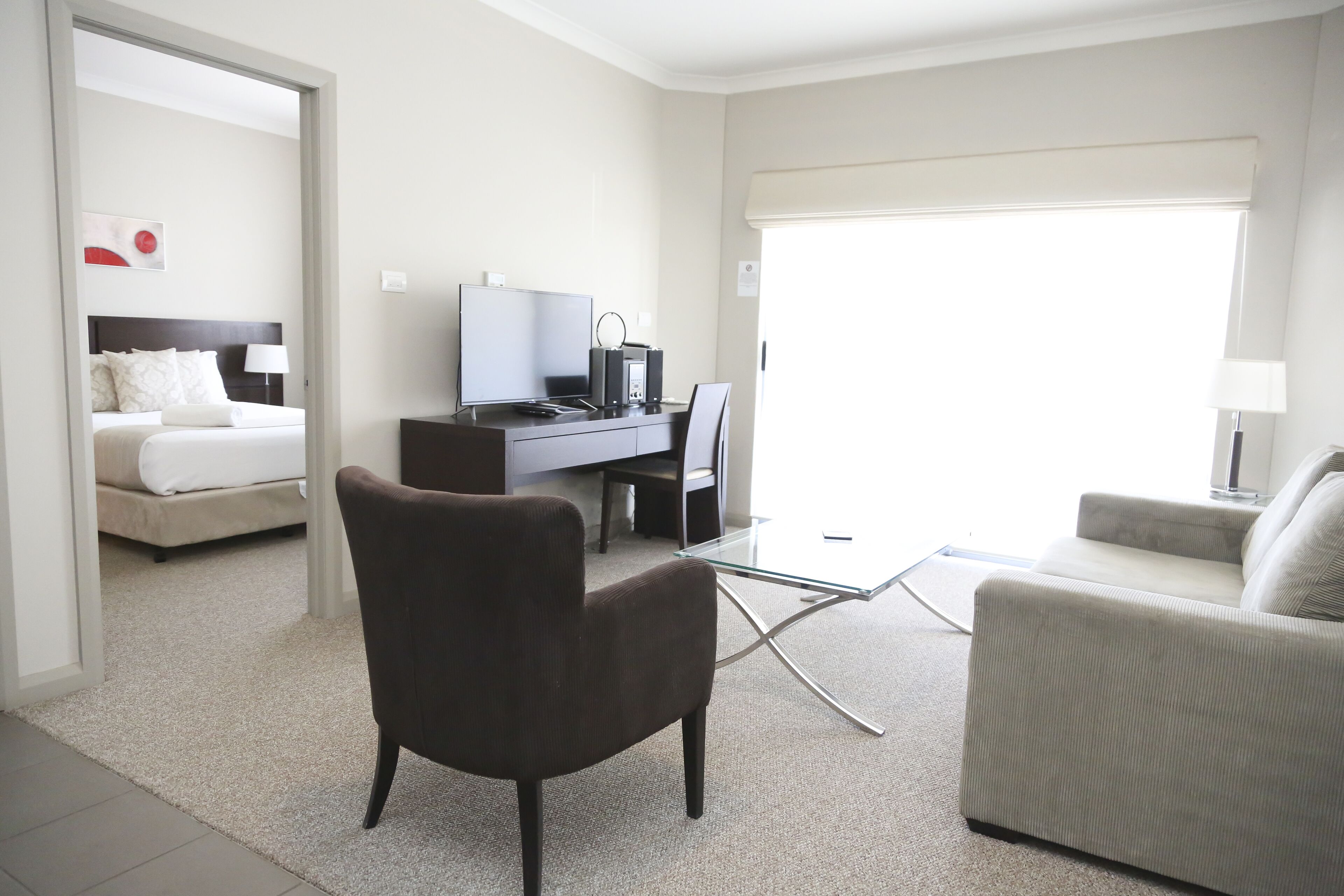 A hotel room with a bed, a desk with a computer, a chair, and a sofa.