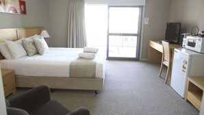 A hotel room with a bed, a desk, a microwave, and a TV.