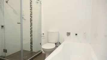A bathroom with a glass shower enclosure, a toilet, and a bathtub.