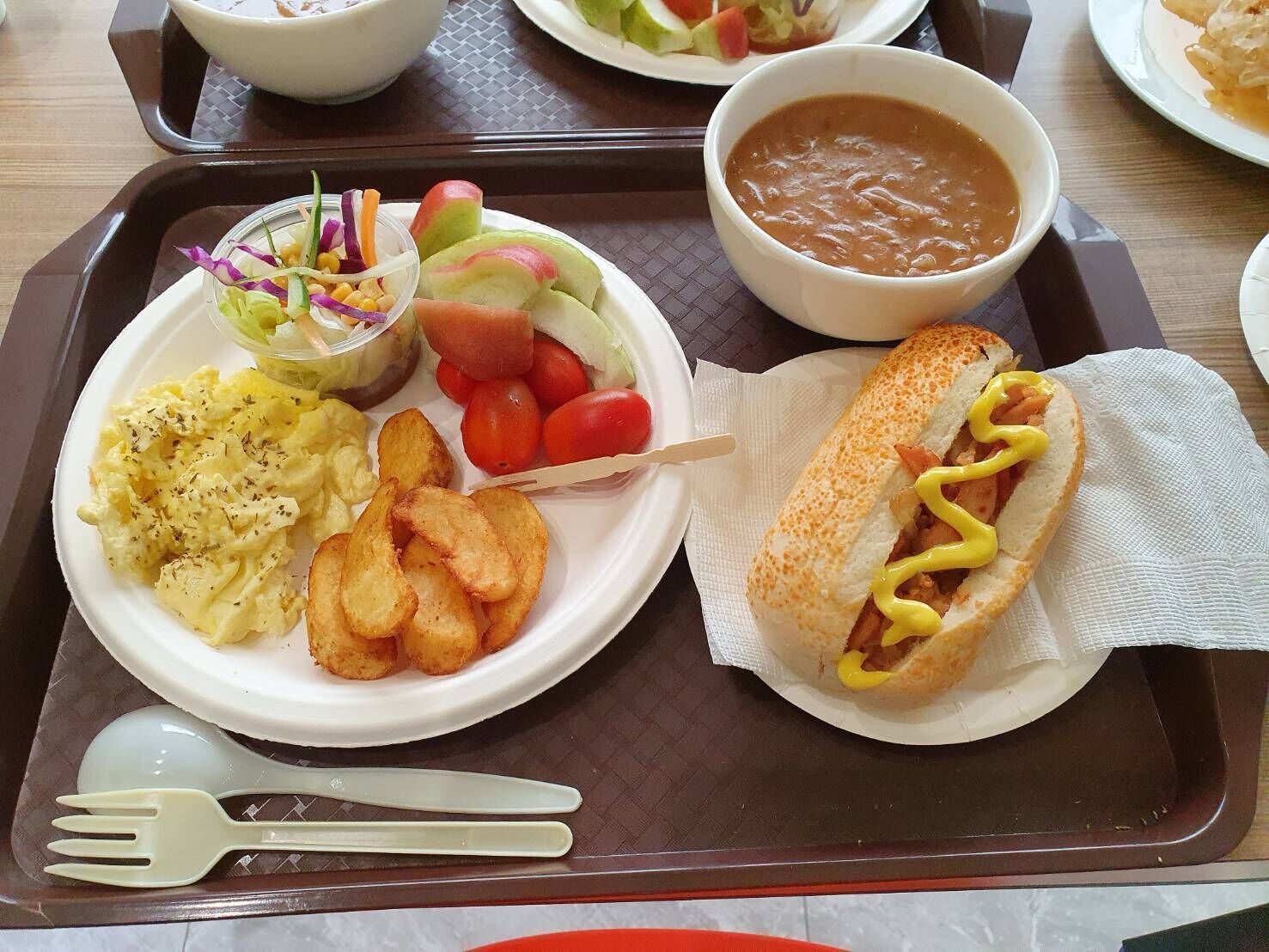 Una bandeja con un sándwich, ensalada de repollo, papas fritas y un tazón de sopa.