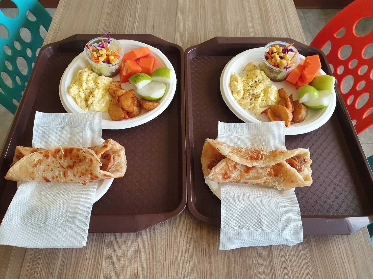 Dos bandejas con comida que incluye huevos revueltos, cuñas de patata y verduras.